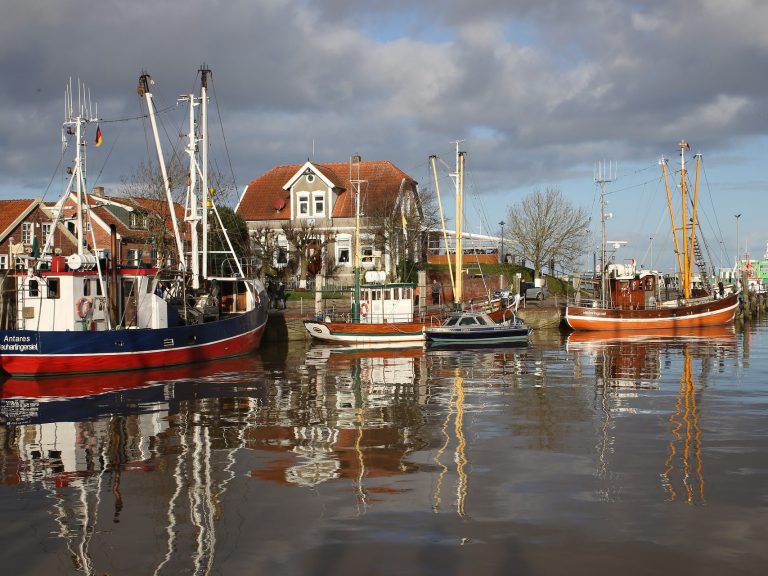 Hafenansicht mit Fischerbooten und einem historischen Gebäude am Wasser.