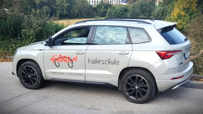 Silberner SUV mit schwarzem Dach und Logo auf der Seitentür.